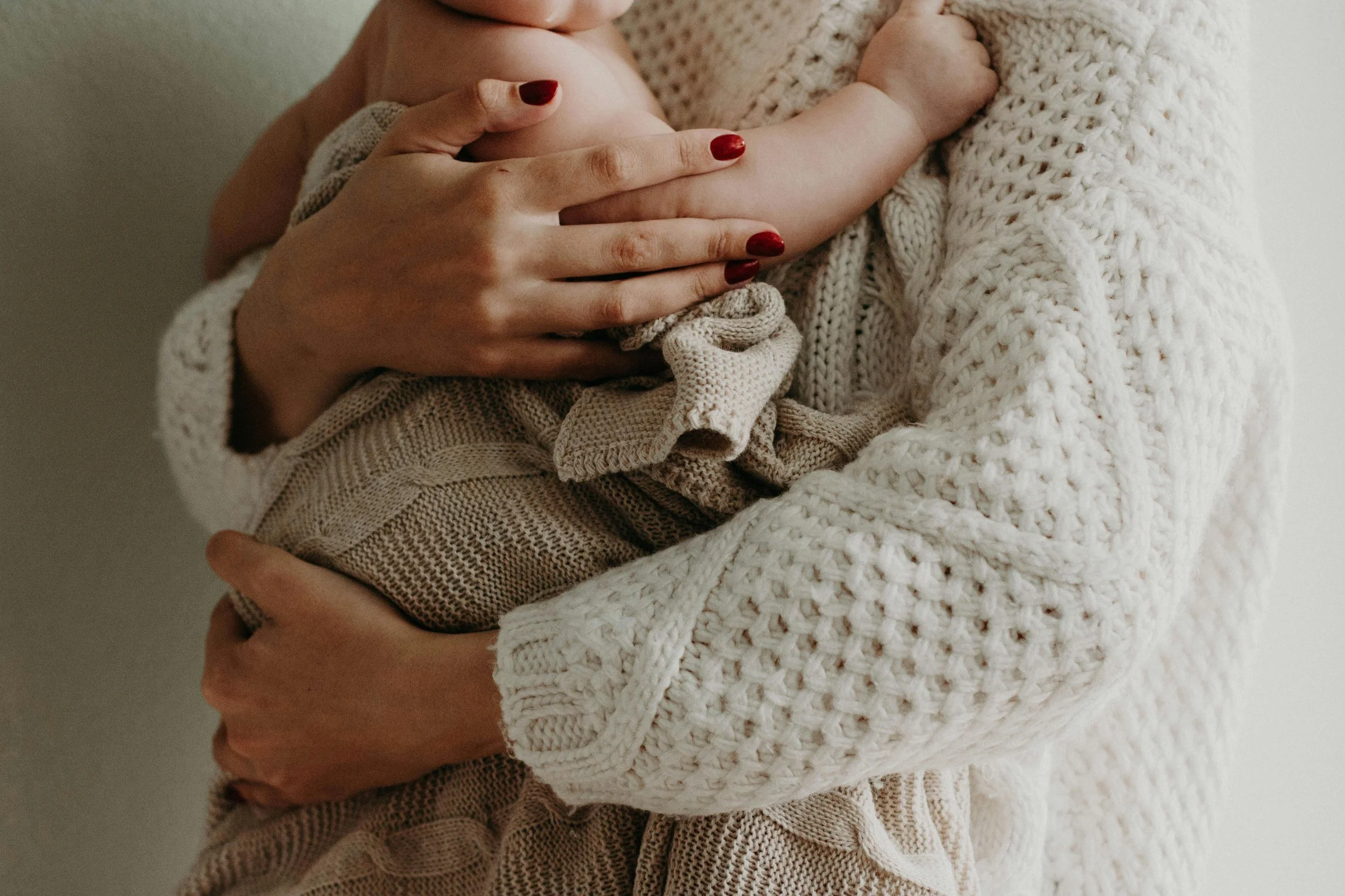 A mother in a cosy knitted jumper holding her baby close