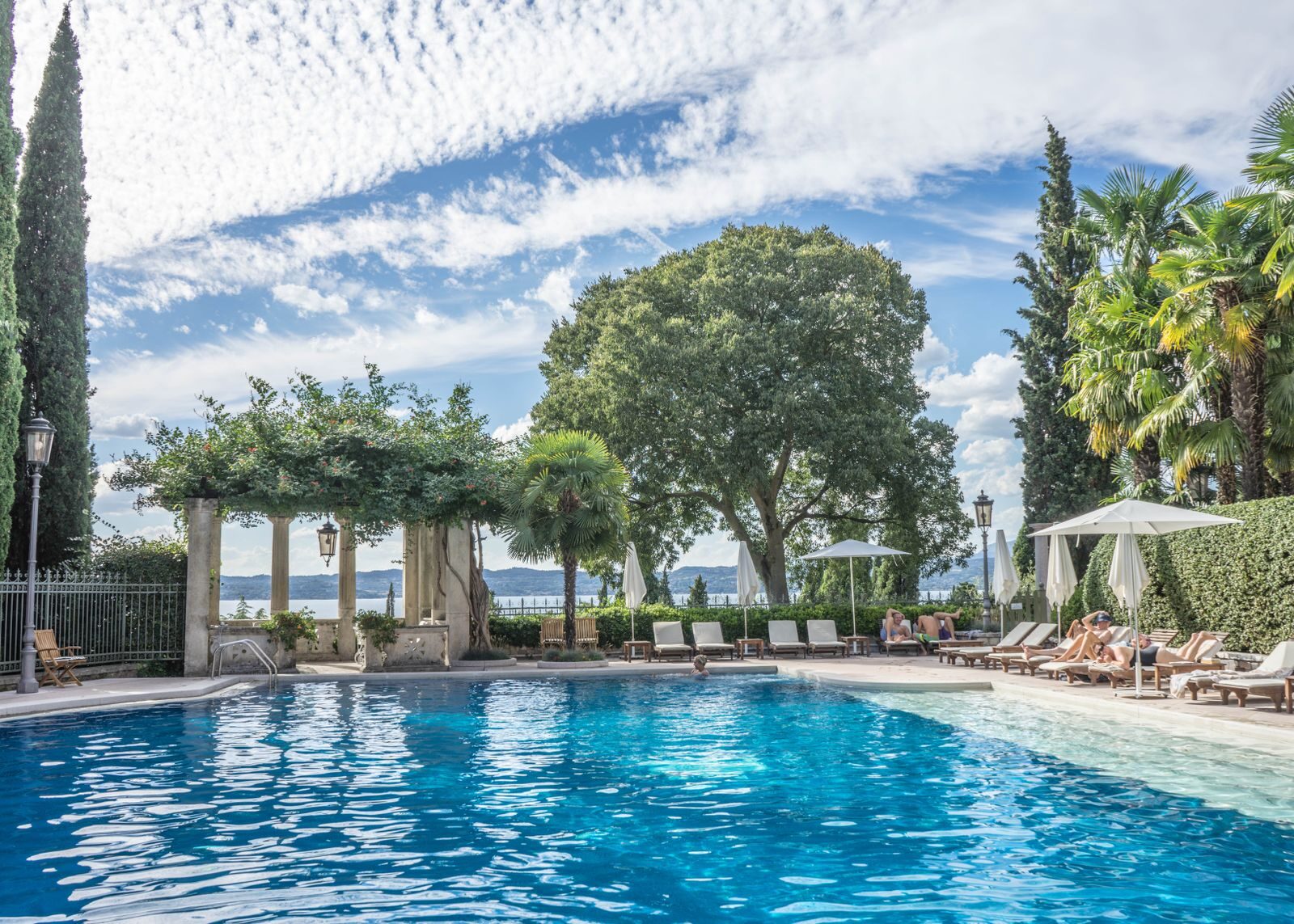 A lakeside villa pool with cypress trees looking out over an Italian lake